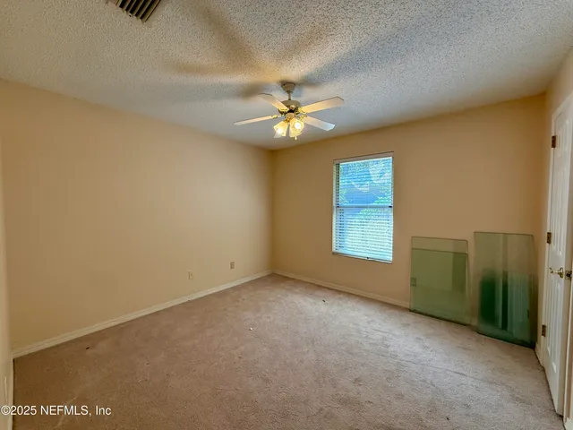an empty room with a window and a ceiling fan