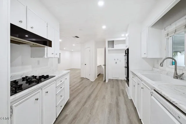 a kitchen with granite countertop white cabinets and stainless steel appliances