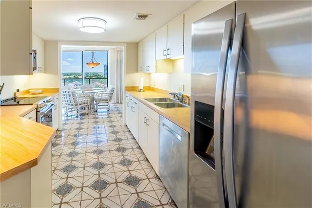 a kitchen with granite countertop a sink a stove top oven and cabinetry