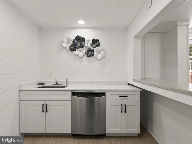 a view with cabinets a sink and wooden floor