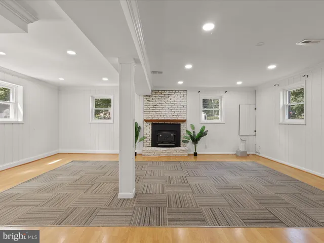 a view of an empty room with wooden floor and a fireplace