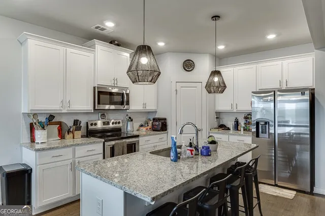 a kitchen with stainless steel appliances granite countertop a sink a stove cabinets and refrigerator