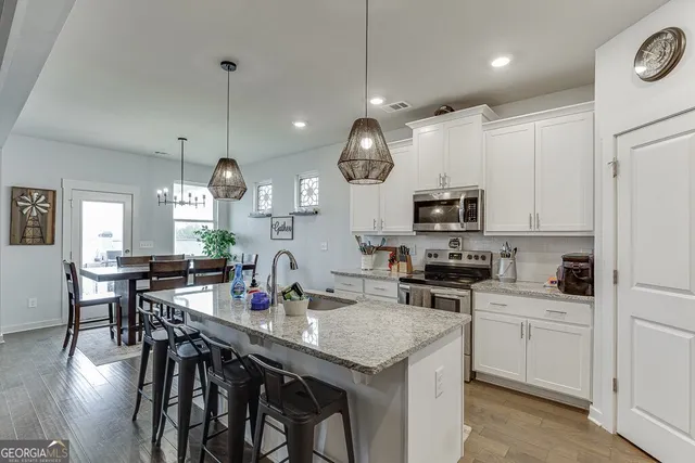 a kitchen with stainless steel appliances granite countertop a stove a microwave a dining table and chairs with wooden floor