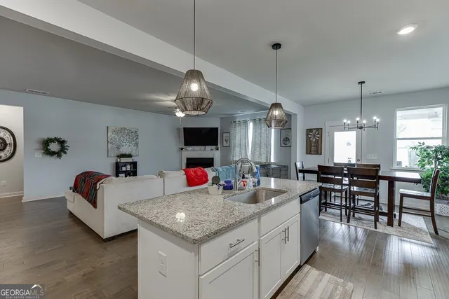 a open kitchen with stainless steel appliances granite countertop a stove oven a dining table and chairs with wooden floor