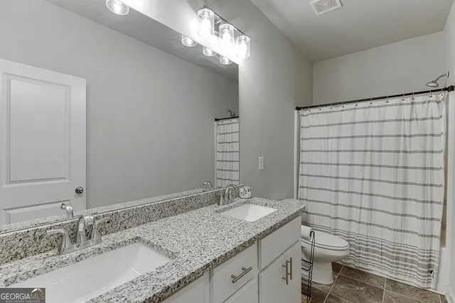a bathroom with a granite countertop sink toilet and mirror