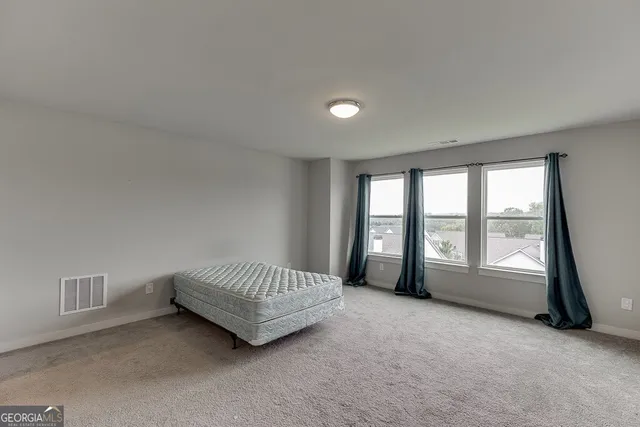 a spacious bedroom with a bed and a large window