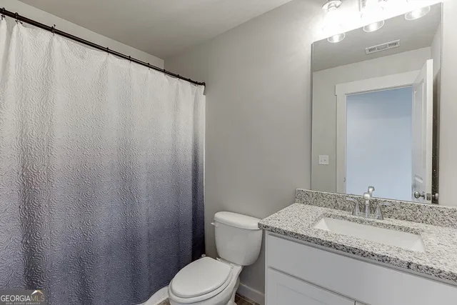 a bathroom with a granite countertop sink toilet and a mirror