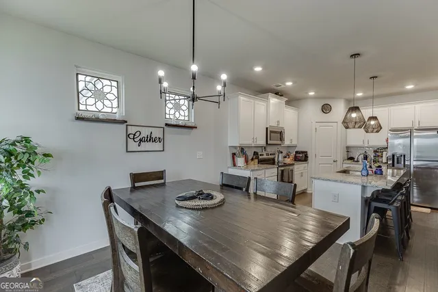 a large kitchen with sink a refrigerator and chairs