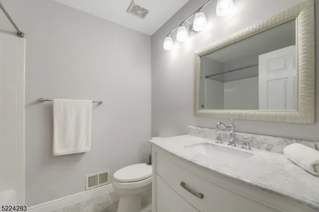 a bathroom with a granite countertop sink a toilet and a mirror