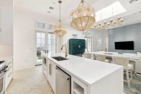 a large kitchen with a large island in the center a sink a window and a clock on the wall