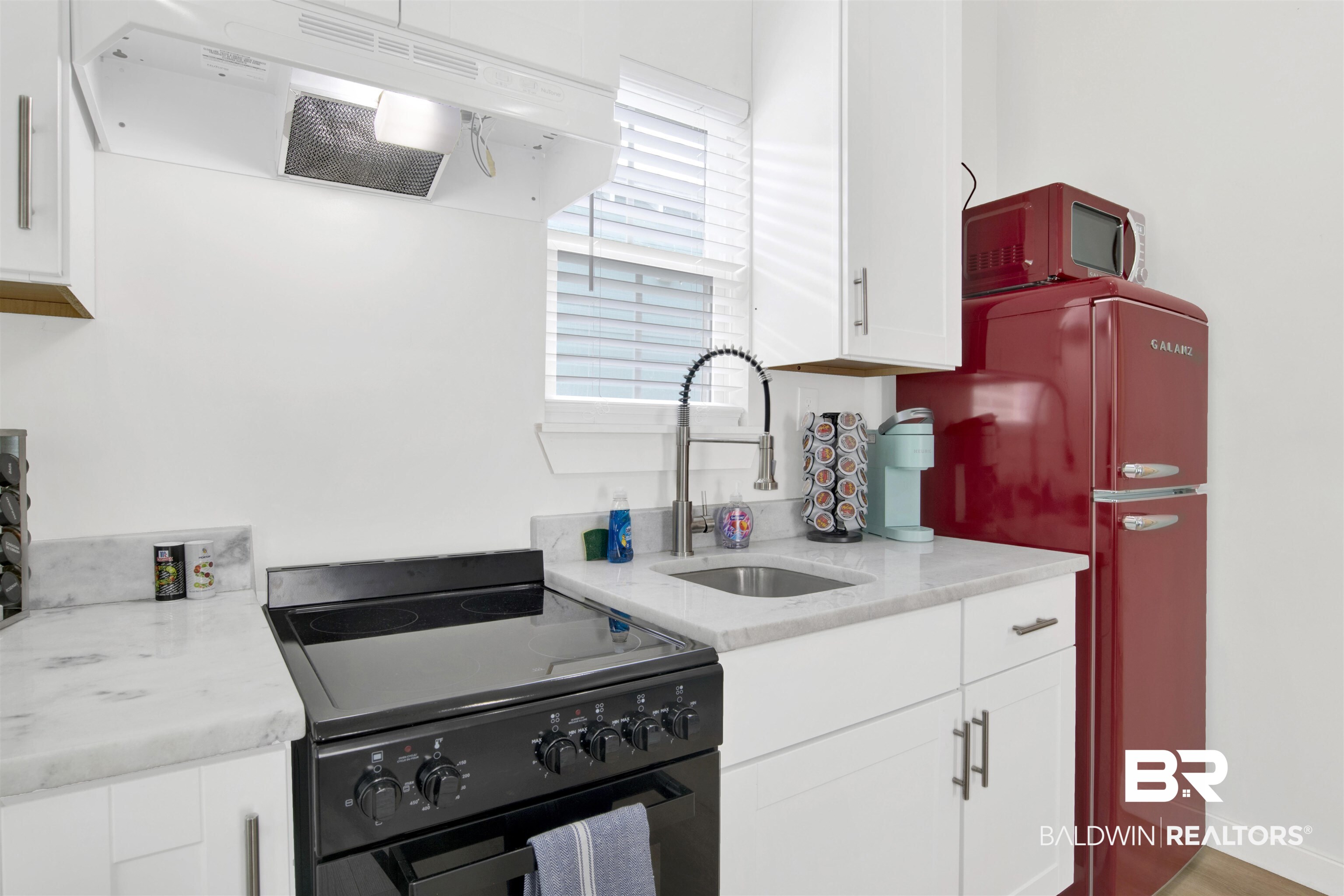 555 Congress Street Mobile, AL 36603 - Photo 25 of 27 Kitchen featuring black electric range oven, exhaust hood, light stone countertops, white cabinetry, and freestanding refrigerator