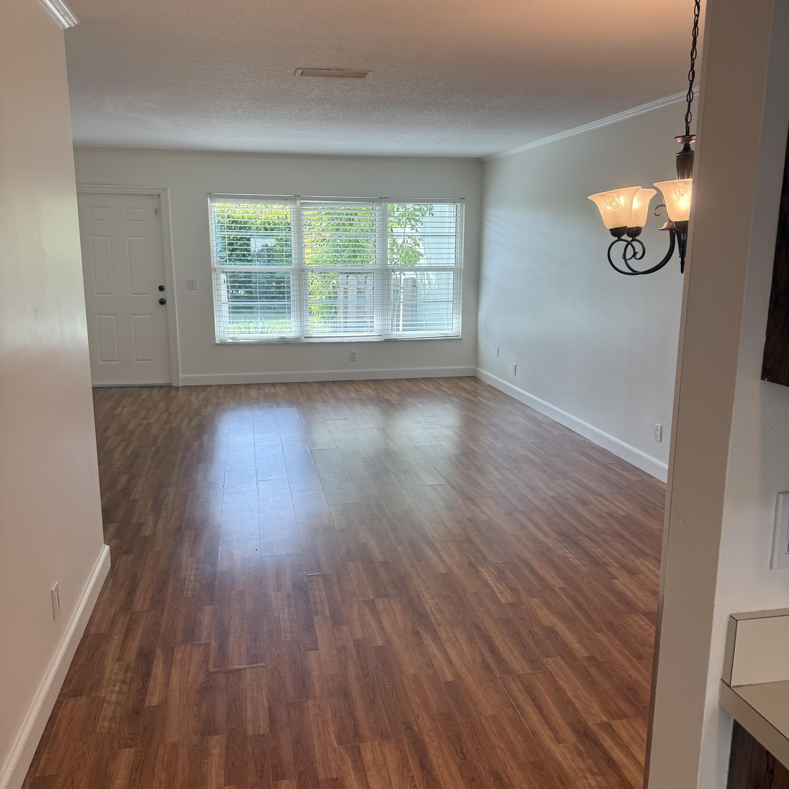 431 Jupiter Lakes Boulevard, Unit 2112A Jupiter, FL 33458 - Photo 4 of 19 an empty room with wooden floor and windows