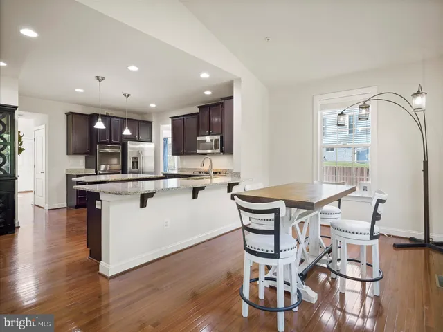 a kitchen with granite countertop kitchen island stainless steel appliances a dining table and chairs