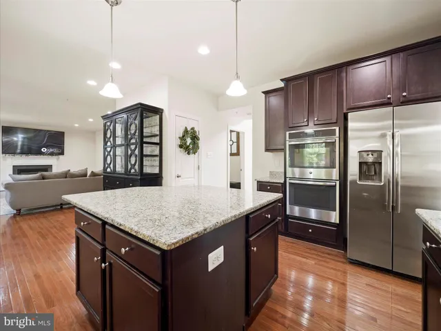 a kitchen with kitchen island a counter space a refrigerator and a sink