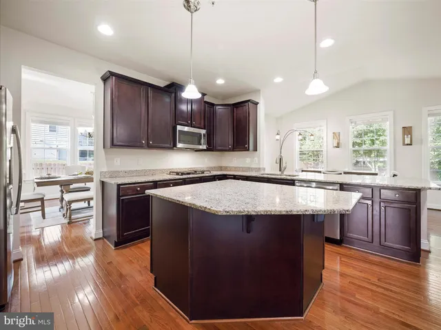 a kitchen with stainless steel appliances granite countertop wooden floors a stove a sink and a refrigerator