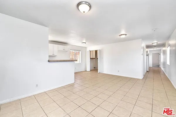 an empty room with kitchen view and a window