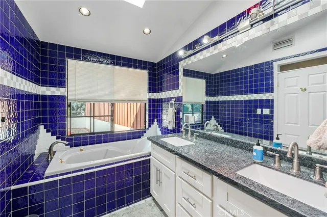 a bathroom with a granite countertop sink and bathtub