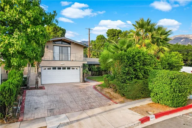 a view of a house with small yard plants and large tree