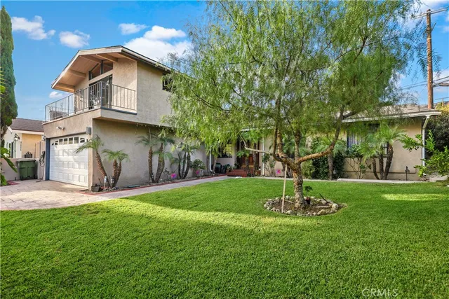 a front view of a house with a yard and tree