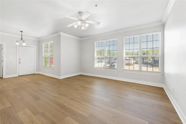 a view of an empty room with a window and wooden floor