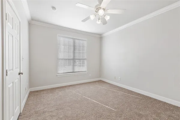 an empty room with a chandelier fan and windows