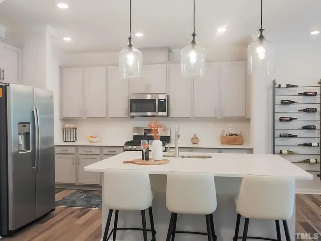 a kitchen with stainless steel appliances a dining table chairs refrigerator and microwave