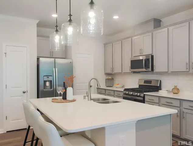 a kitchen with stainless steel appliances a sink a stove a refrigerator and cabinets