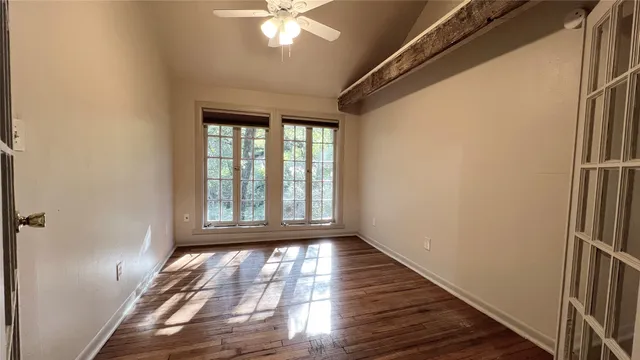 a view of empty room with wooden floor and fan