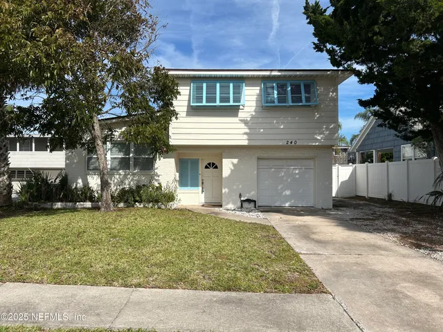 a front view of a house with a garden and trees