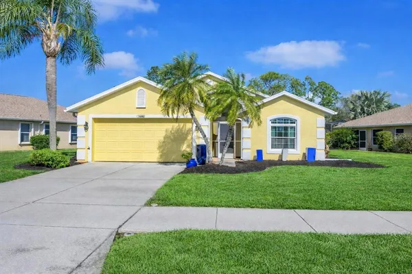 a view of a white house with a small yard and palm trees