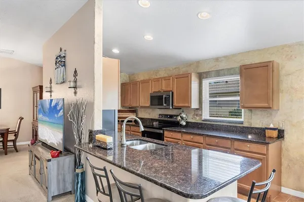 a kitchen with granite countertop a sink a counter top space appliances and cabinets
