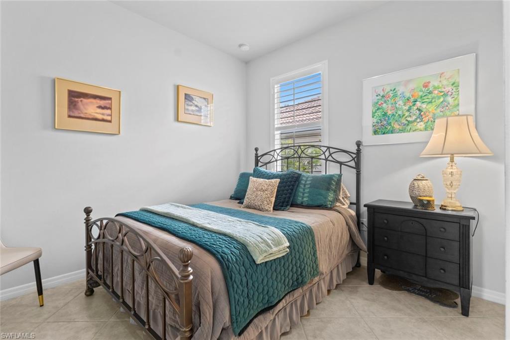 5719 Declaration Court Ave Maria, FL 34142 - Photo 21 of 48 a bedroom with a bed a lamp and a window