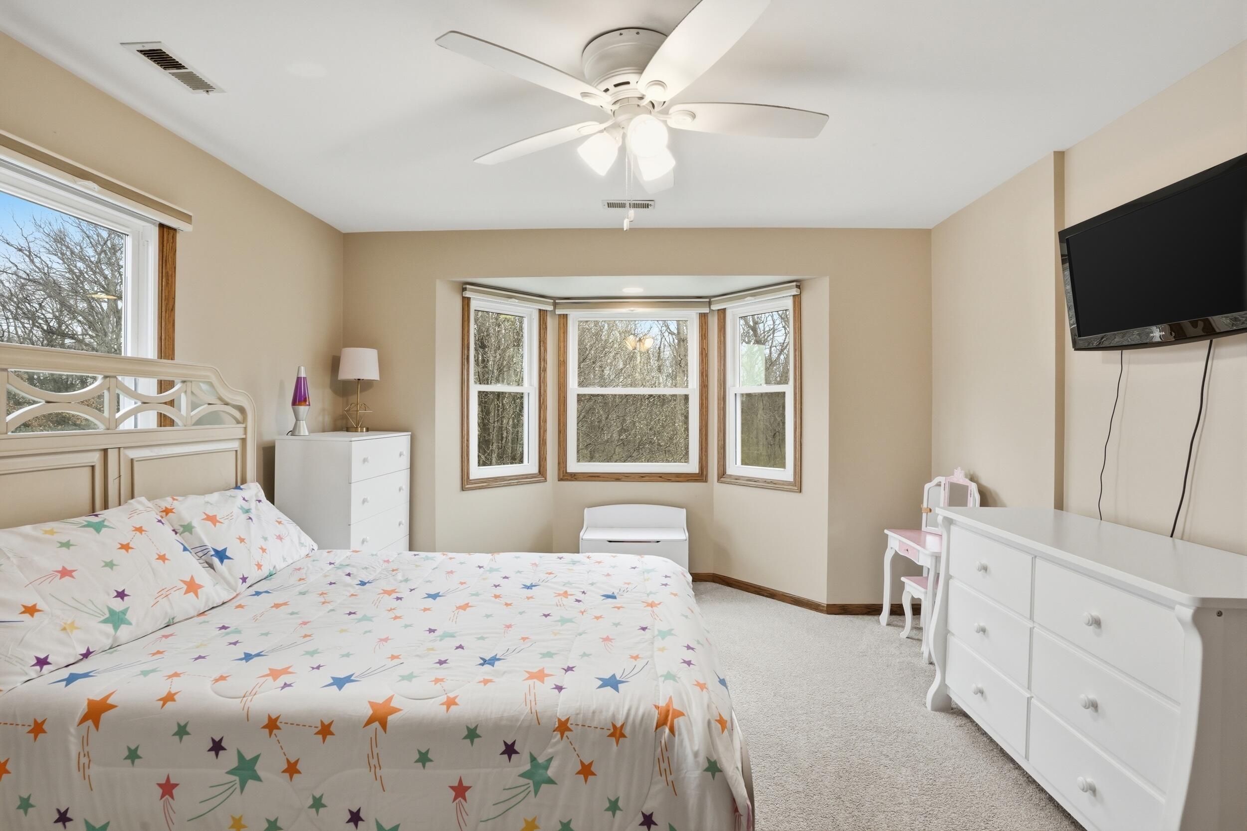1122 Douglas Lane Crete, IL 60417 - Photo 18 of 28 a bedroom with a bed a chandelier and a flat screen tv