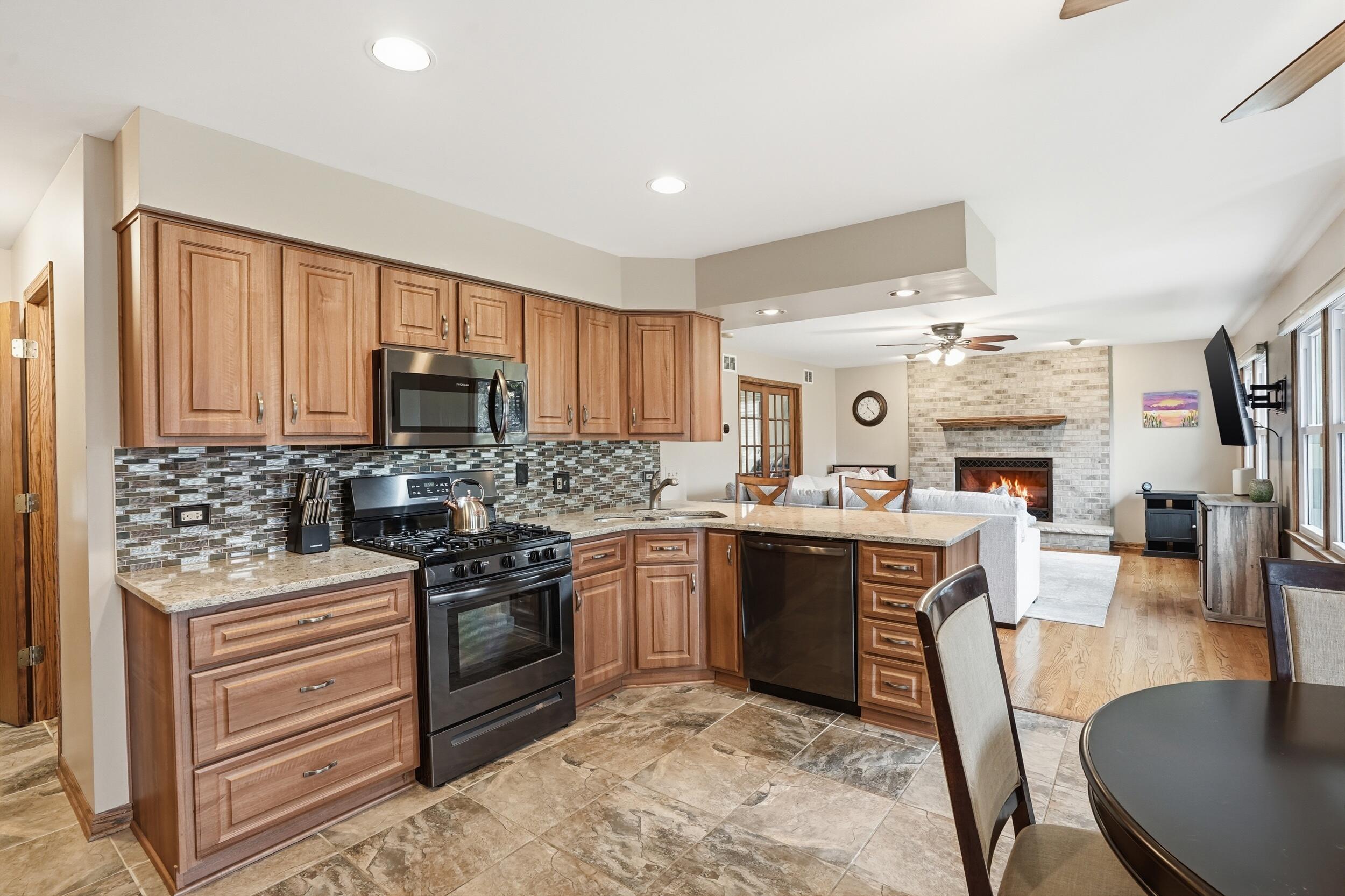 1122 Douglas Lane Crete, IL 60417 - Photo 7 of 28 a kitchen with stainless steel appliances granite countertop a stove top oven a sink dishwasher a dining table and chairs with wooden floor