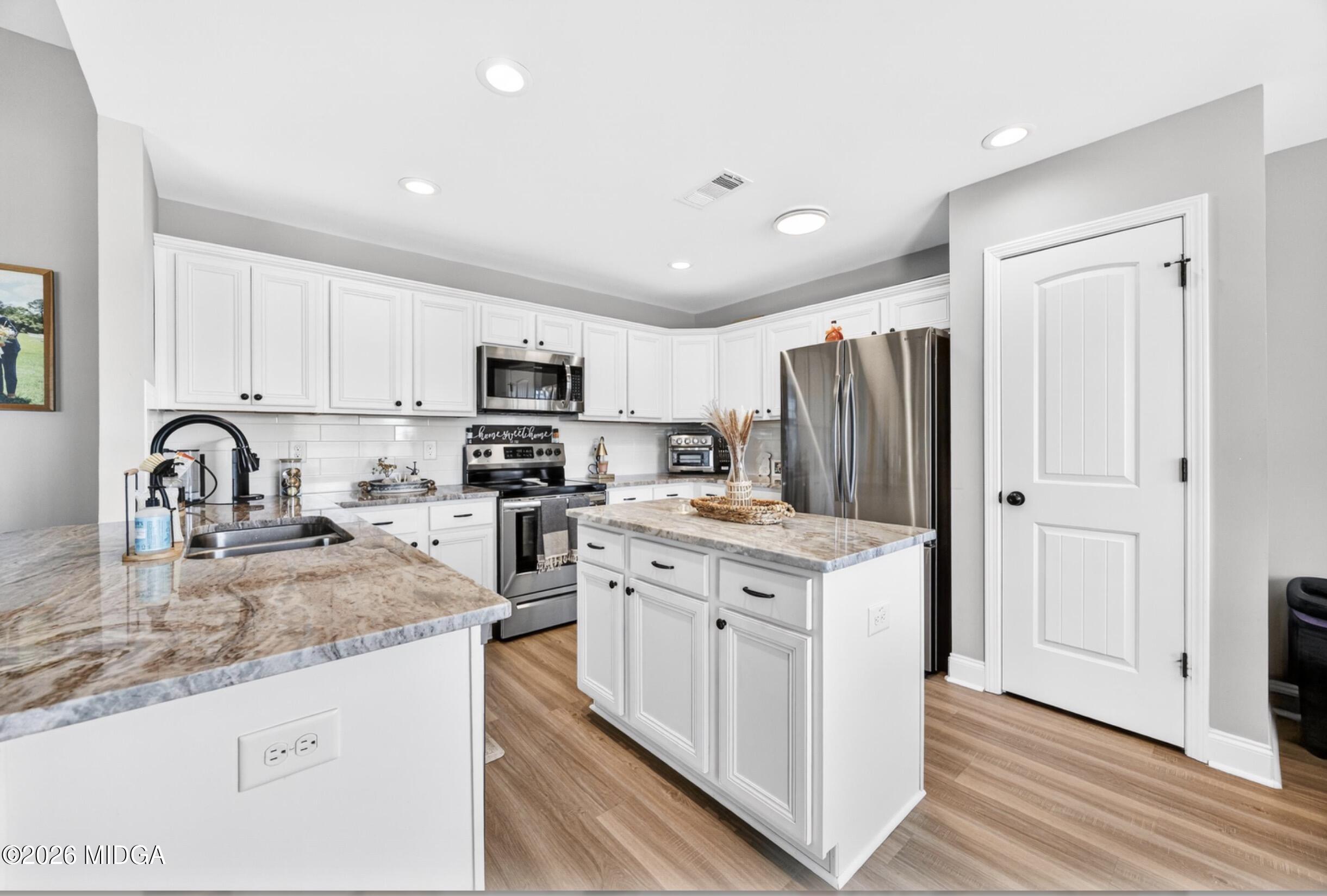 610 Daisy Drive Perry, GA 31069 - Photo 8 of 33 a kitchen with stainless steel appliances granite countertop a stove top oven a refrigerator a sink and dishwasher with wooden floor