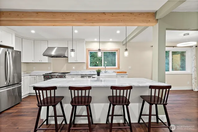 a kitchen with stainless steel appliances a dining table chairs and wooden floor