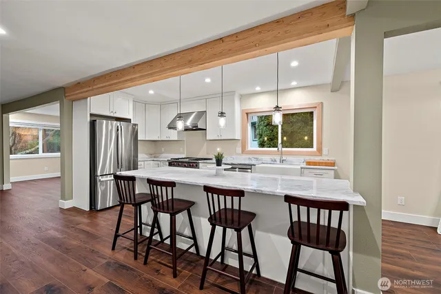 a kitchen with stainless steel appliances a dining table chairs and wooden floor