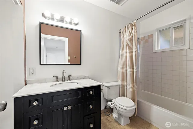 a bathroom with a toilet sink vanity tub and mirror