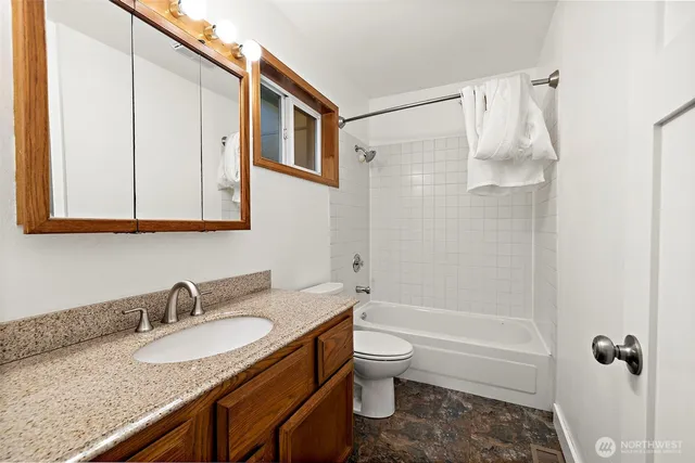 a bathroom with a granite countertop sink toilet and shower