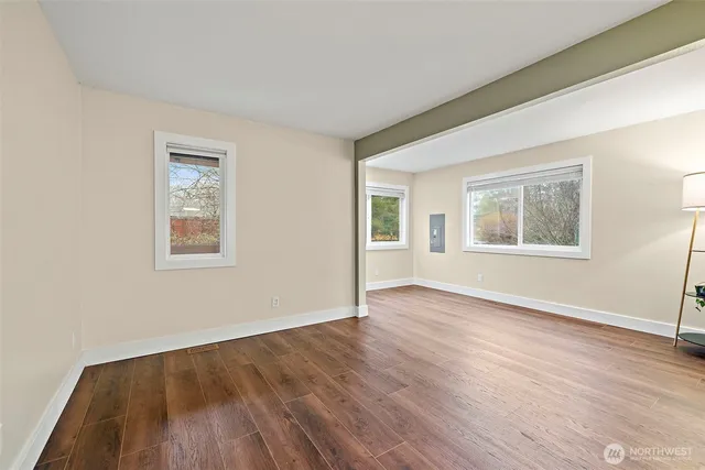 a view of an empty room with wooden floor and a window