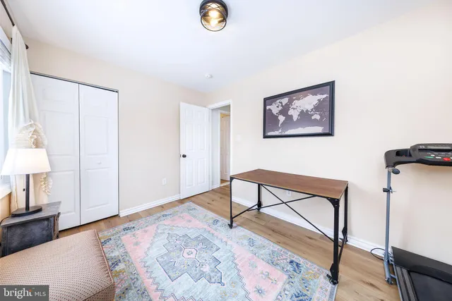 a view of a hallway to a livingroom with wooden floor and furniture
