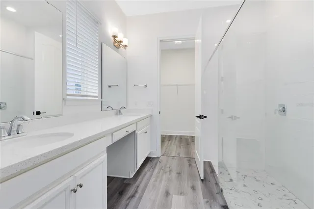 a spacious bathroom with a double vanity sink a mirror and a shower