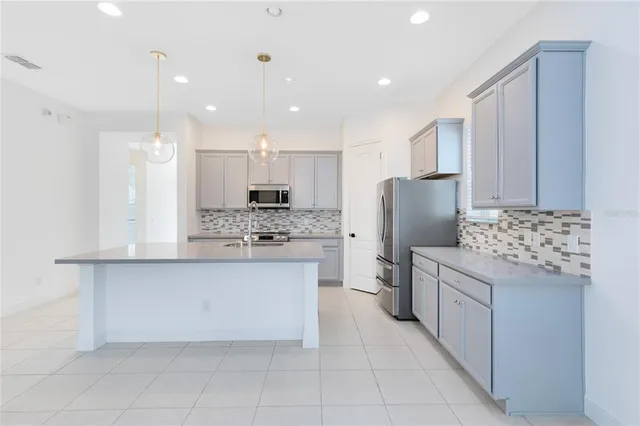 a kitchen with stainless steel appliances kitchen island granite countertop a refrigerator and a stove top oven