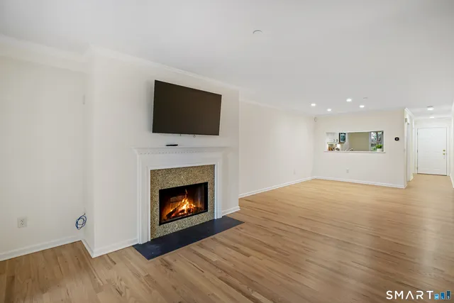 a view of an empty room with wooden floor fireplace and a window