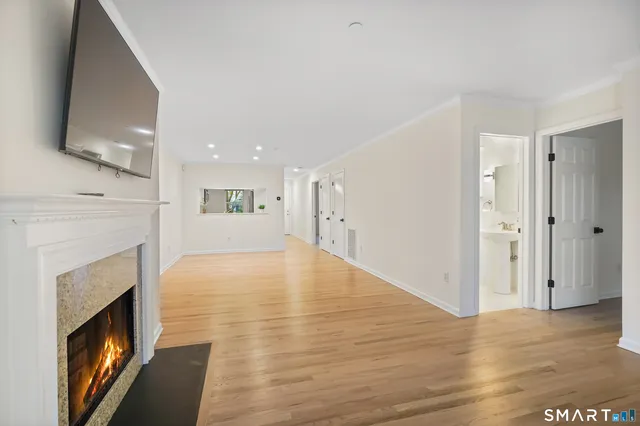 a view of an empty room with wooden floor and a fireplace