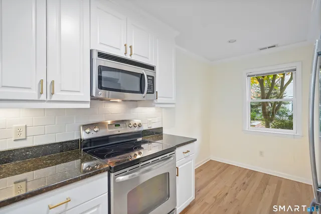 a kitchen with granite countertop cabinets stainless steel appliances and wooden floor