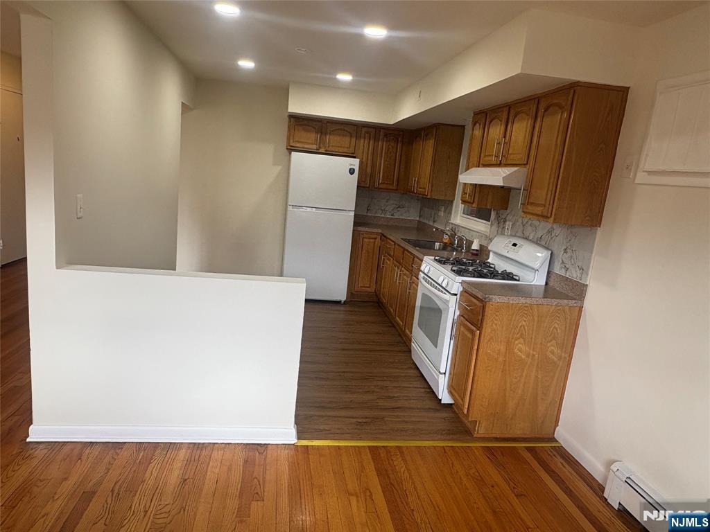 399 Walker Street, Unit 1B Fairview, NJ 07022 - Photo 5 of 11 a kitchen with wooden floors a refrigerator and a stove