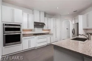 a kitchen with granite countertop white cabinets and stainless steel appliances