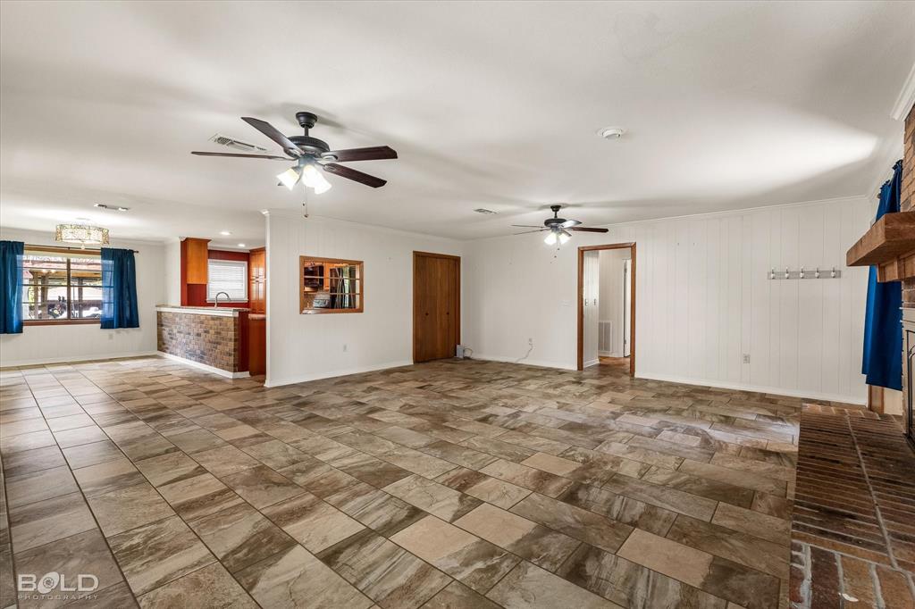 225 Marie Road Ringgold, LA 71068 - Photo 22 of 40 Spacious living area featuring large format tile flooring, a brick fireplace with a wood mantle, and two ceiling fans