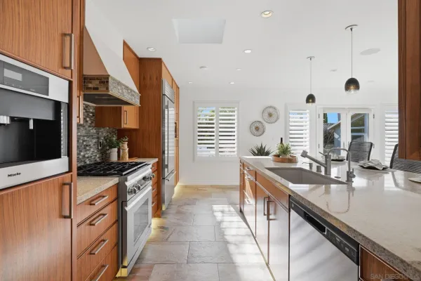 a large kitchen with stainless steel appliances a sink and cabinets